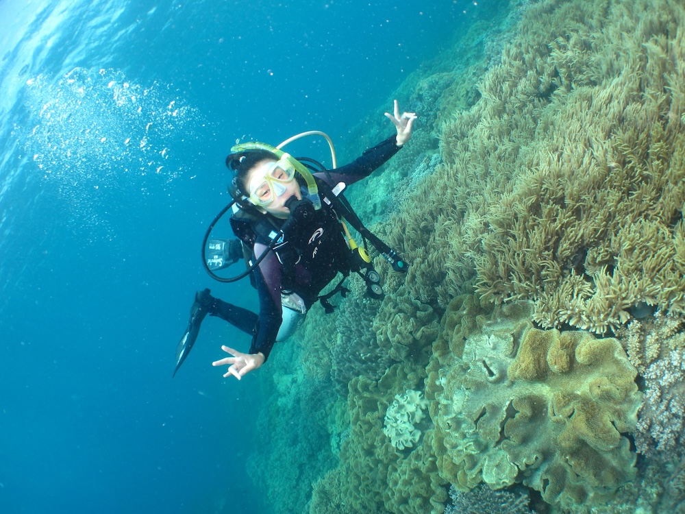 サンゴの上を泳ぐ女性ダイバー